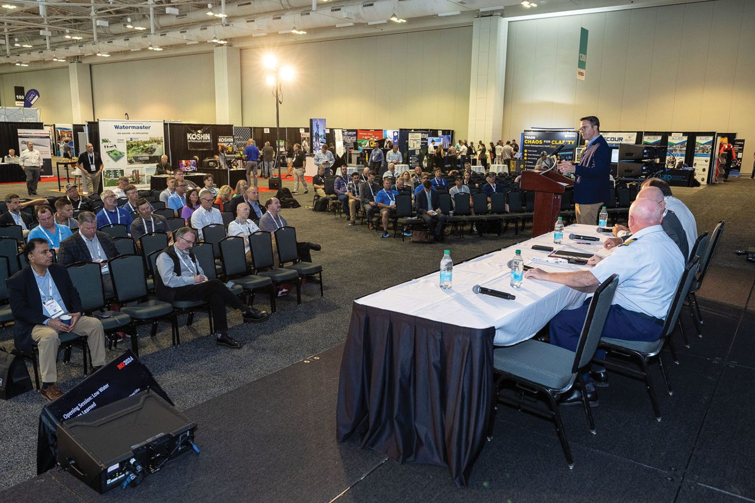 Justin Lampert (standing), director of the American Waterways Operators mid-continent office, moderates a panel on “Low Water Lessons Learned” during IMX 2024. (Photo by Event Coverage Nashville)